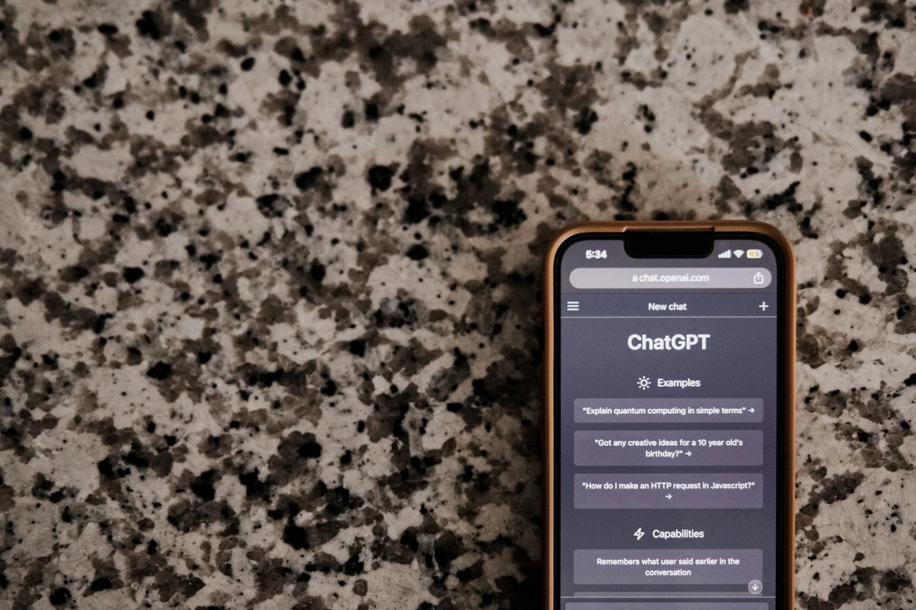 Close-up of a smartphone with ChatGPT interface on a speckled surface, highlighting technology and AI.