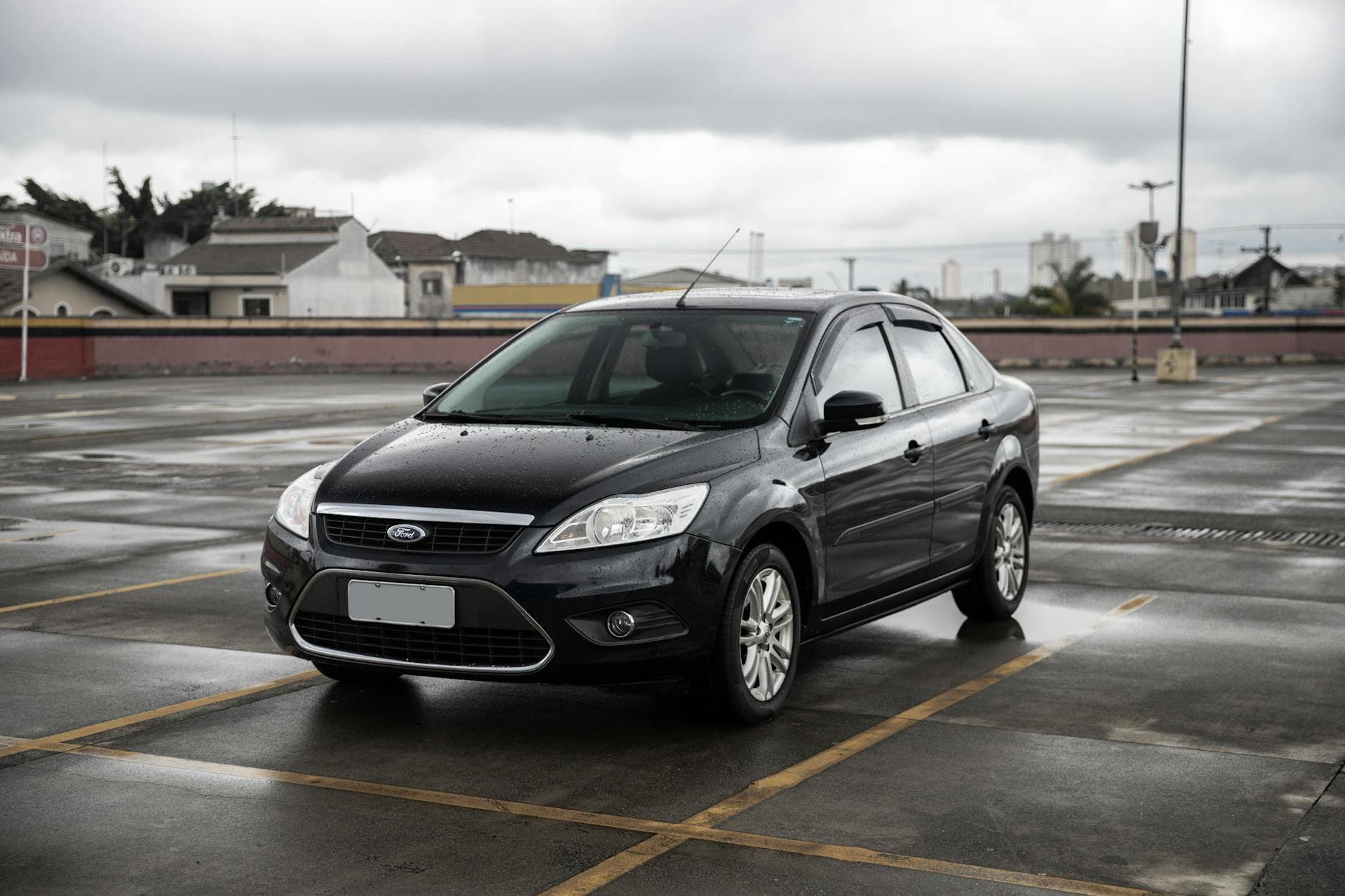 Black Ford sedan parked in a spacious São Paulo parking lot on a cloudy day.
