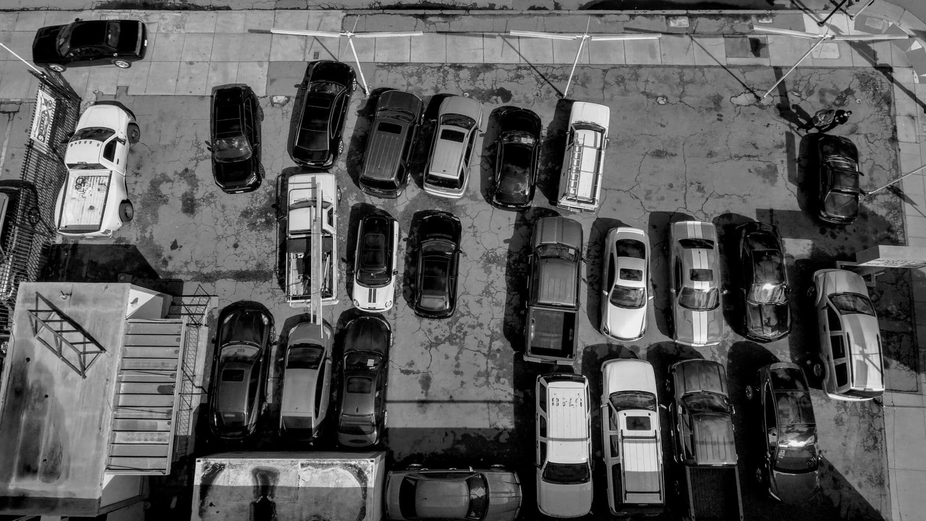 Black and white aerial view of cars in an urban parking lot, Alameda, CA.