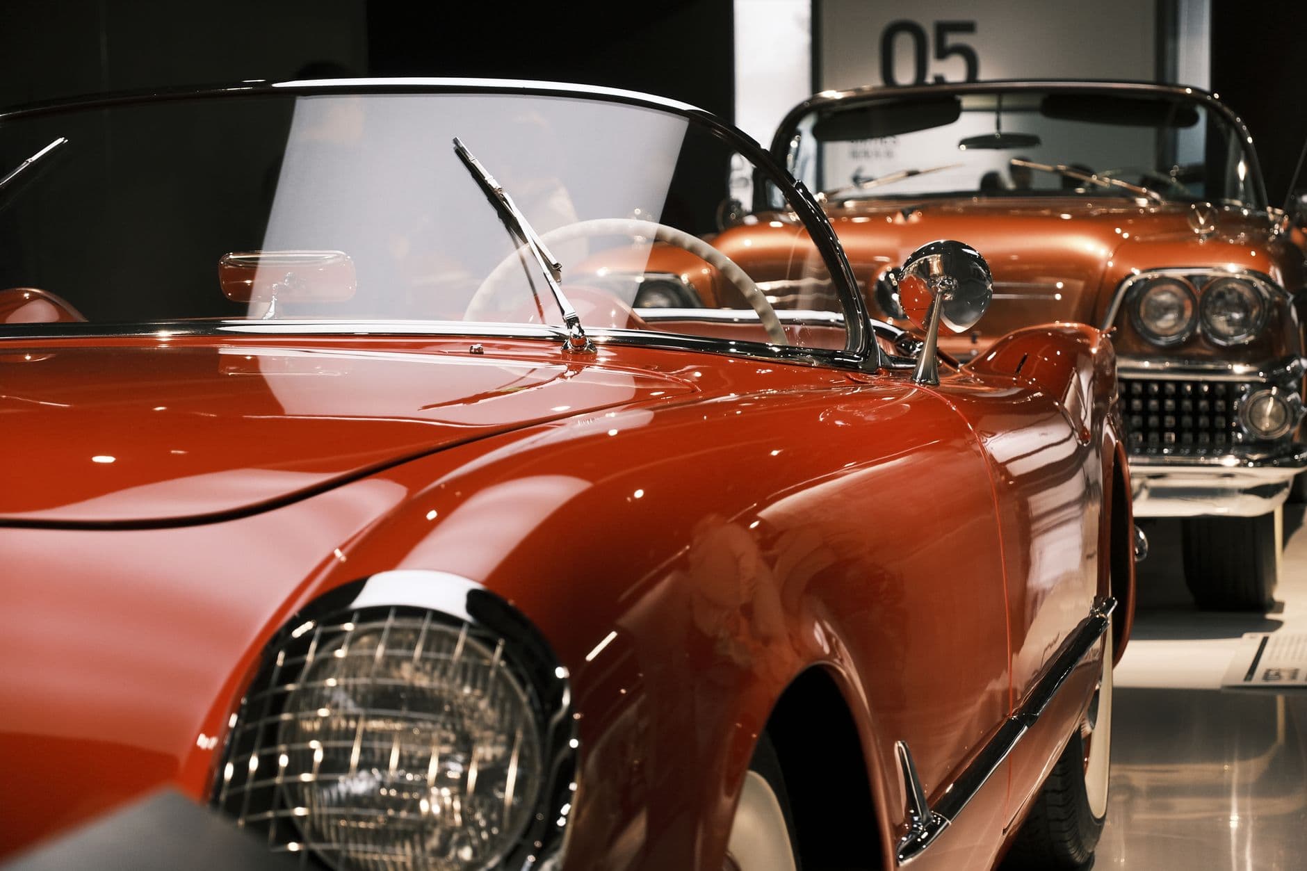 A beautifully preserved vintage red cabriolet showcased at a car exhibition indoors.