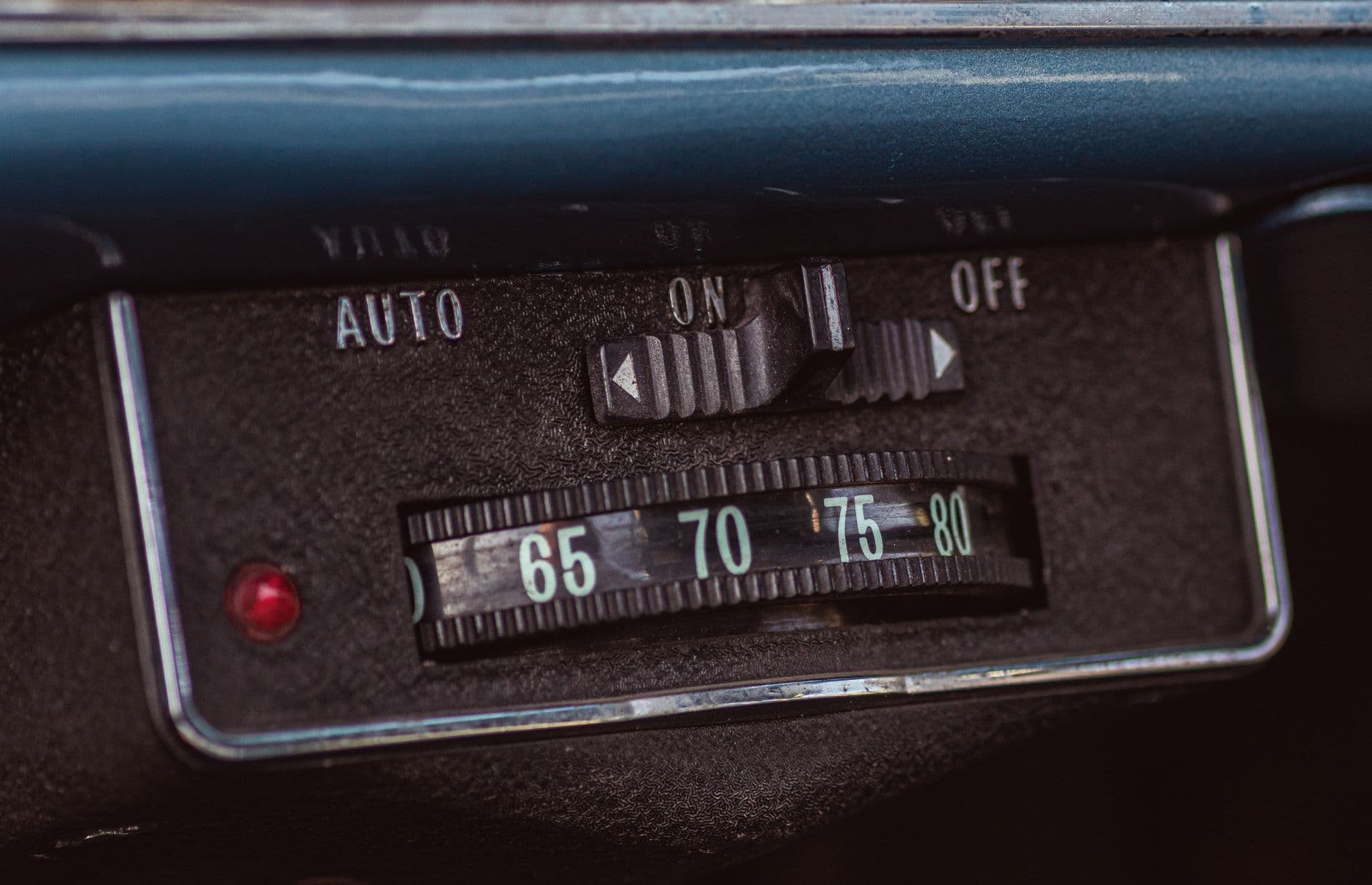 Detailed view of vintage car dashboard showing manual switch and temperature dial from 1960s.