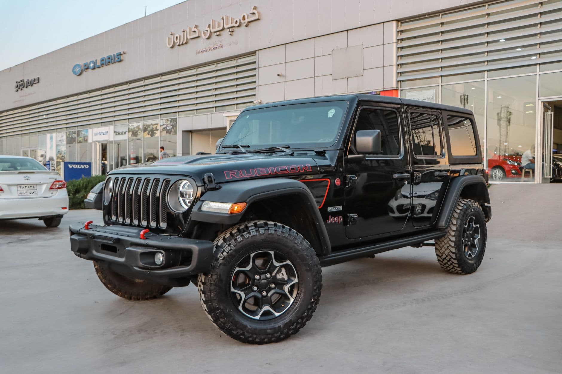 Black Jeep Wrangler Rubicon parked at a dealership showcasing its rugged design and glossy finish.