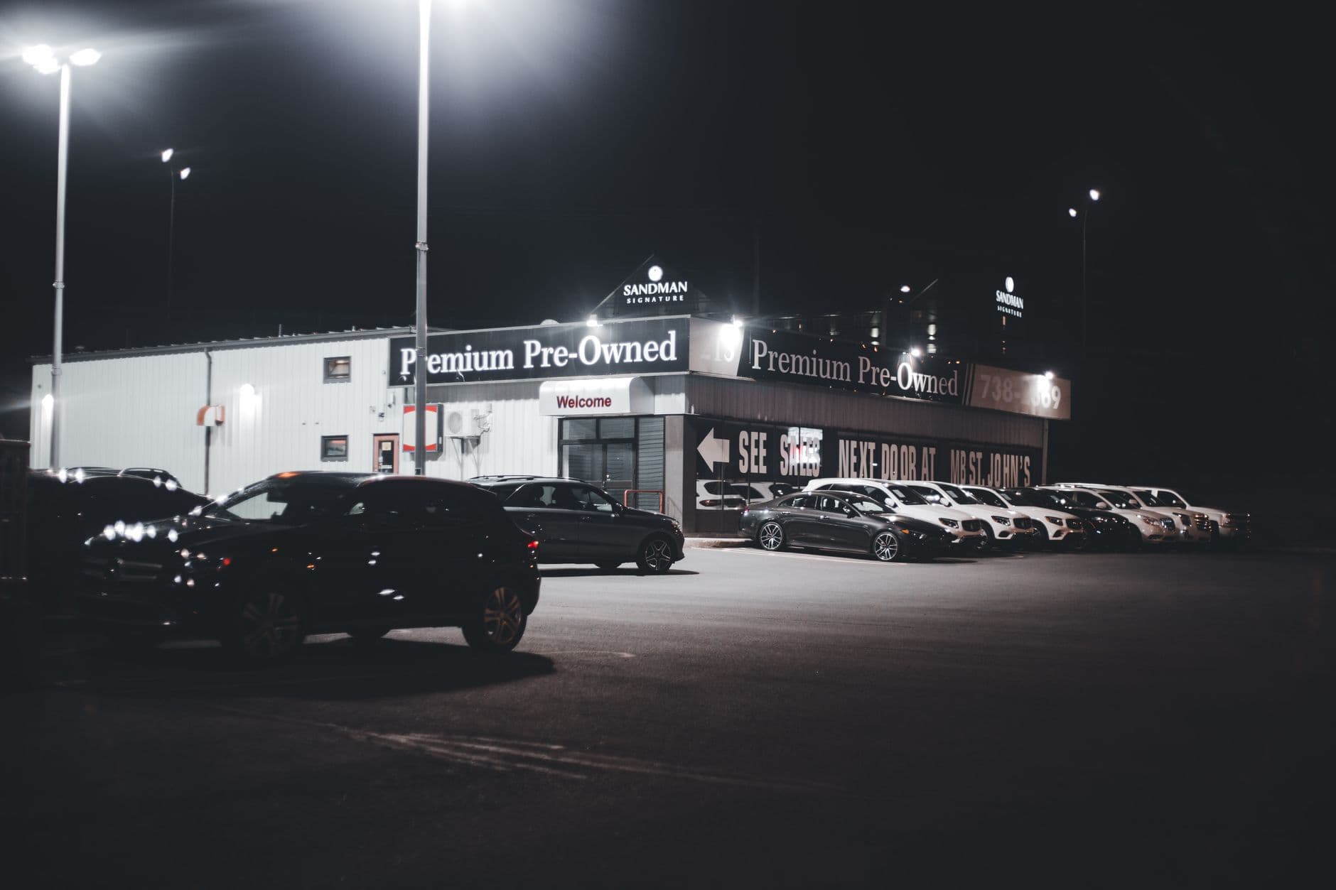 Illuminated car dealership lot showcasing premium pre-owned vehicles at night.
