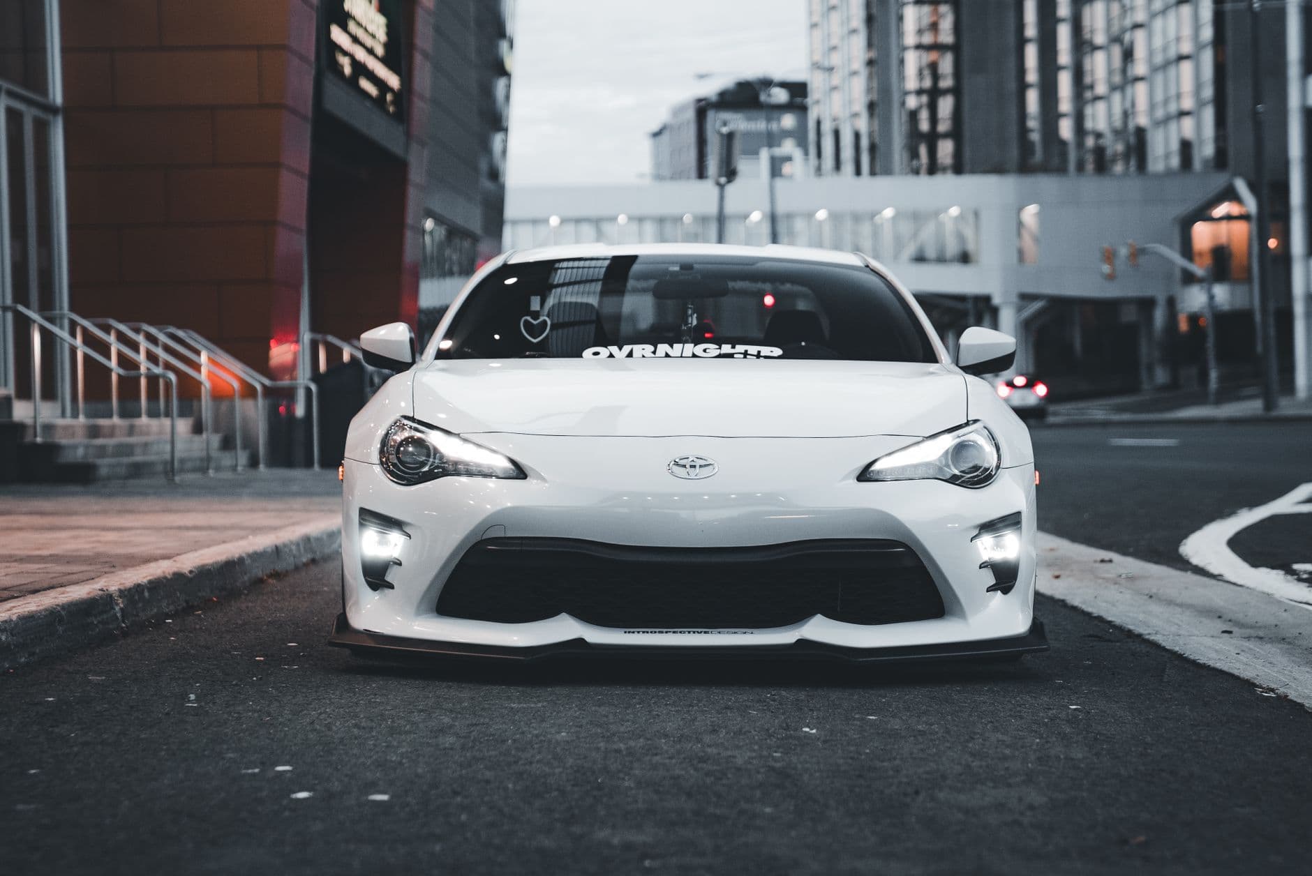 A modern white sports car parked on a city street, showcasing urban automotive style.