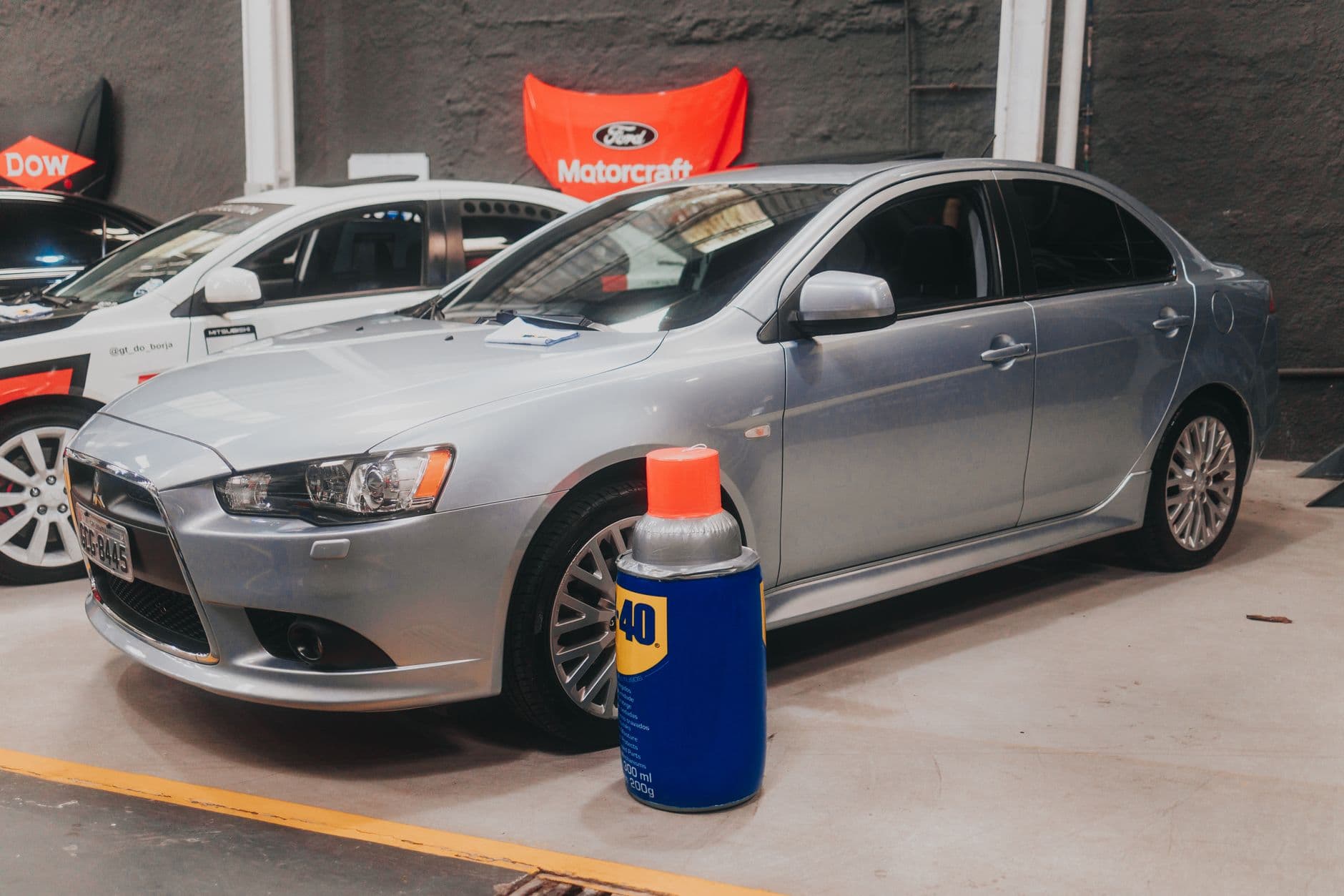 Silver sedan parked indoors alongside WD-40, showcasing garage setting and automotive supplies.