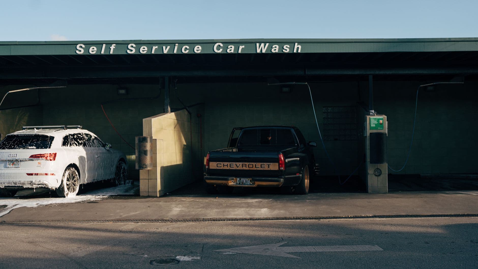 Self service car wash featuring a foam-covered Audi and a Chevrolet truck.