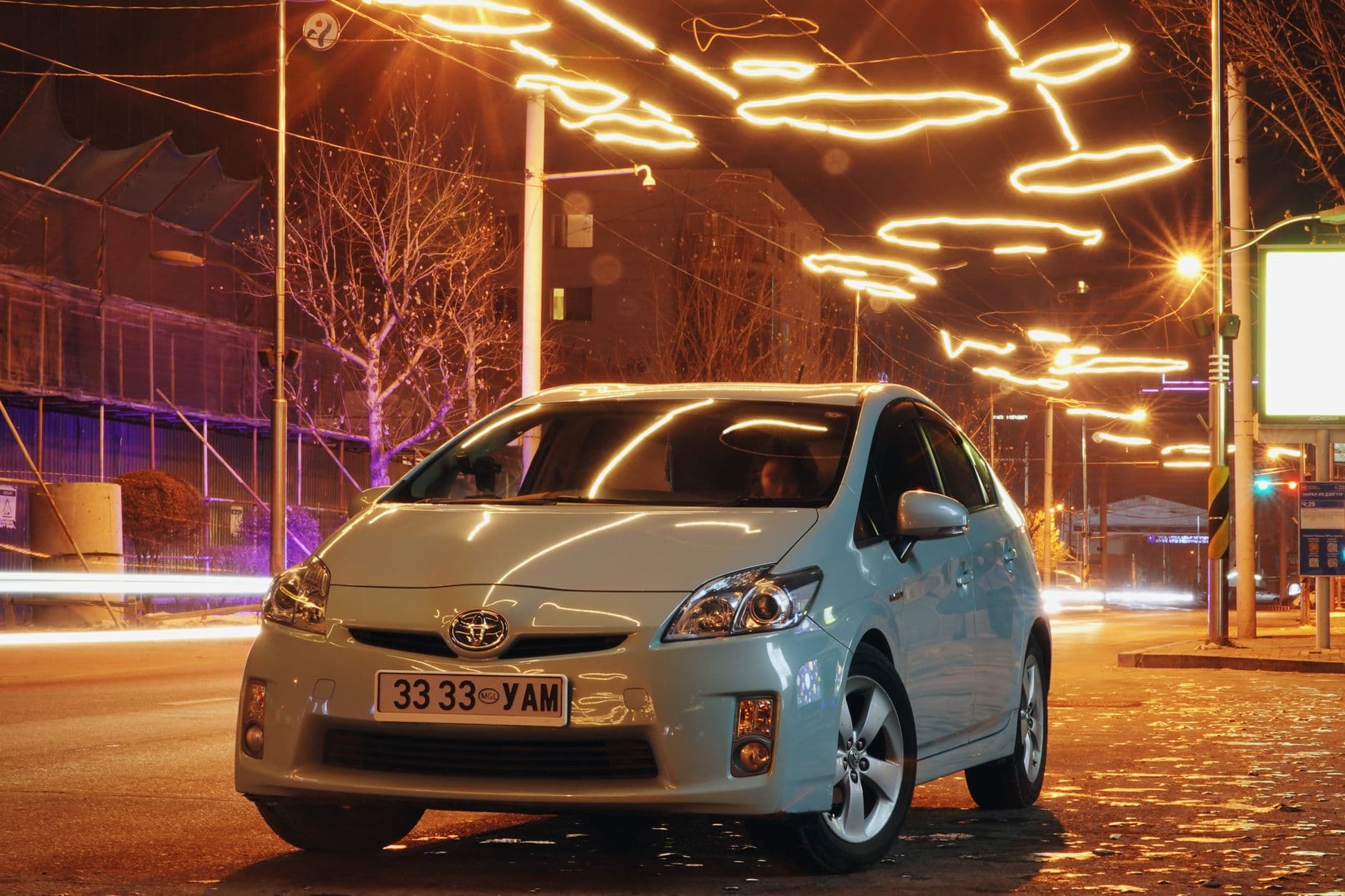 A Toyota car parked on a brightly lit street at night in Ulaanbaatar, Mongolia.