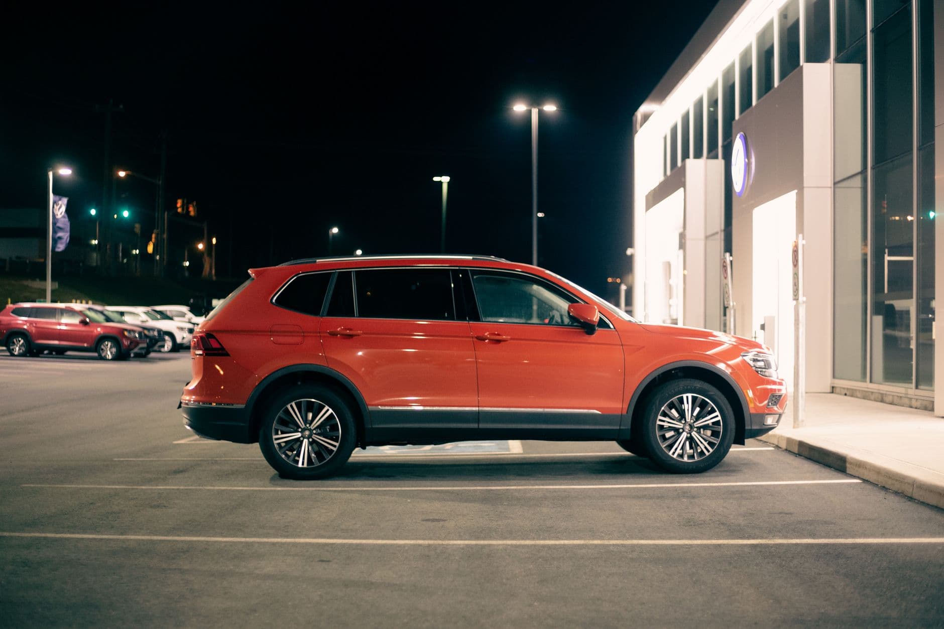 Luxury red off road car with glossy body parked near store entrance at night