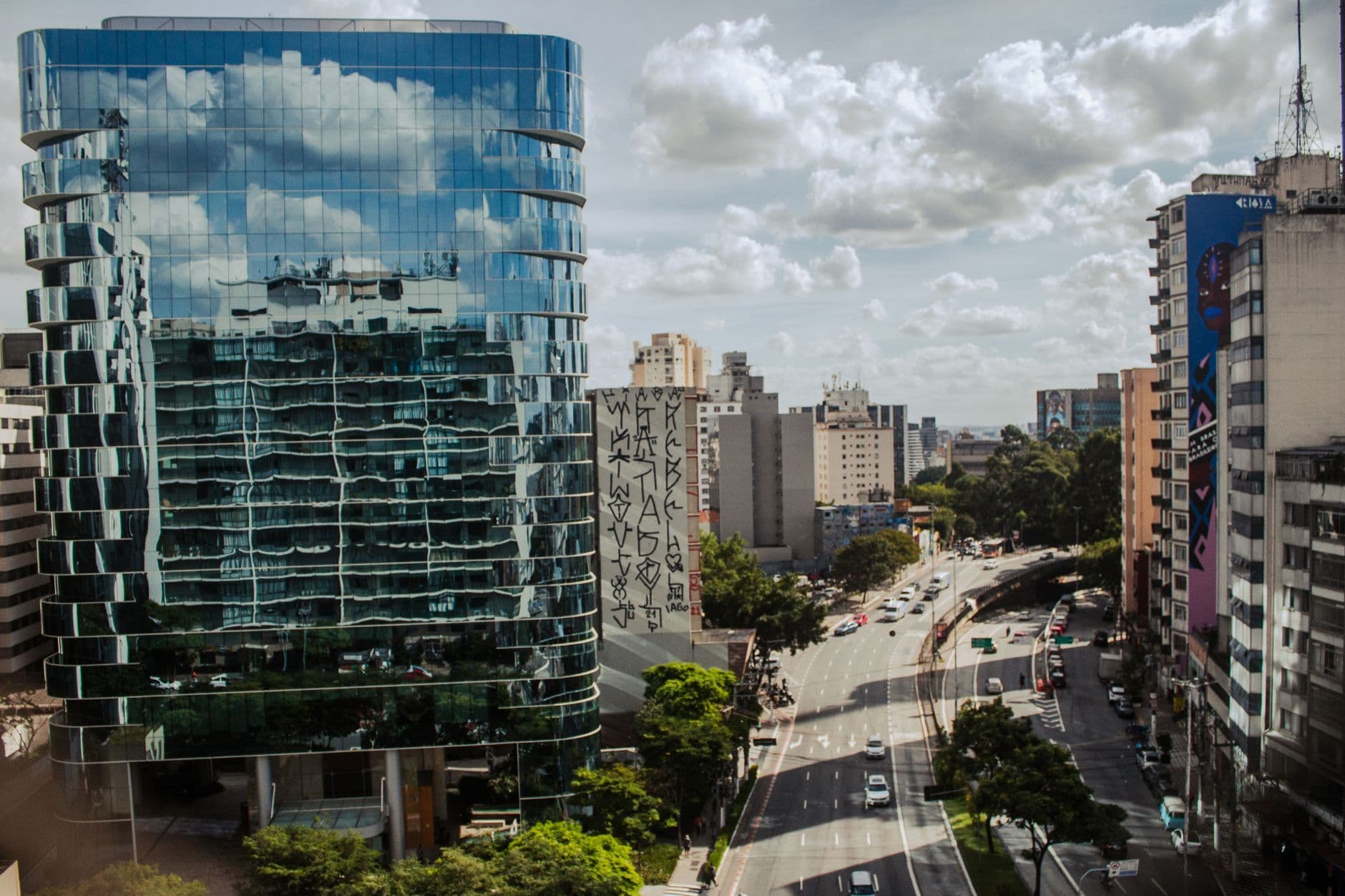 Aerial view of a busy urban street with modern glass buildings and reflected cityscape.